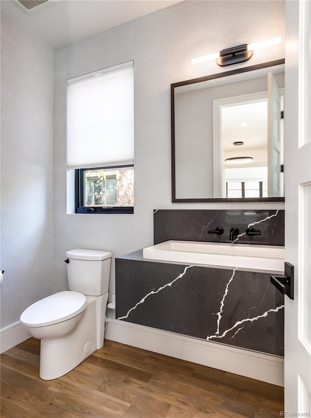 bathroom featuring wood-type flooring and toilet