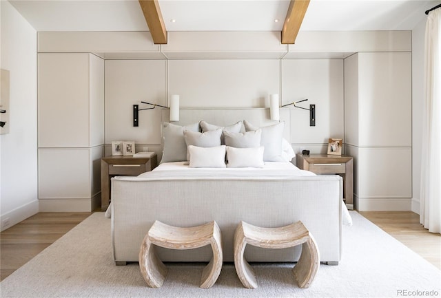 bedroom with beamed ceiling and light wood-type flooring