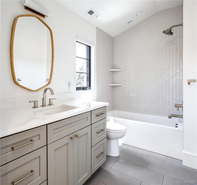 full bathroom featuring tile patterned floors, lofted ceiling, toilet, vanity, and tiled shower / bath