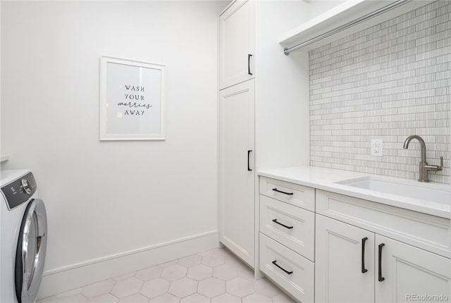 clothes washing area featuring cabinets, light tile patterned flooring, washer / dryer, and sink