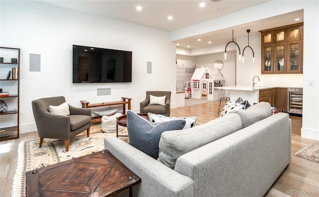 living room featuring sink, beverage cooler, and light hardwood / wood-style flooring