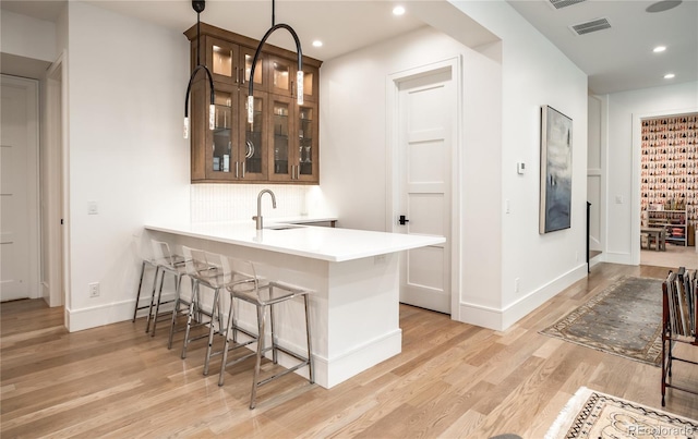 bar featuring sink, light wood-type flooring, and hanging light fixtures