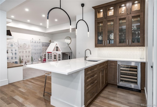 bar featuring hardwood / wood-style flooring, decorative light fixtures, sink, and beverage cooler