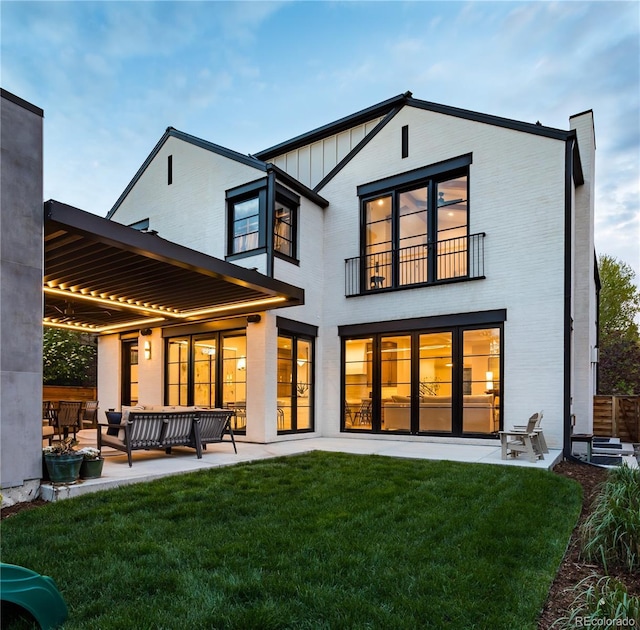 rear view of house featuring outdoor lounge area, a balcony, a yard, and a patio