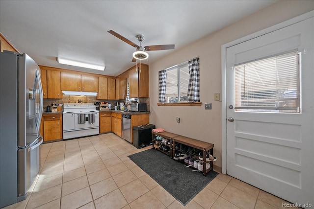 kitchen featuring tasteful backsplash, light tile patterned flooring, ceiling fan, and appliances with stainless steel finishes