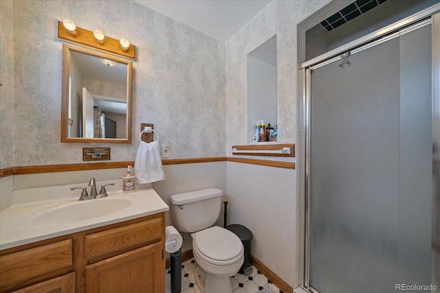 bathroom with vanity, a shower with door, and toilet