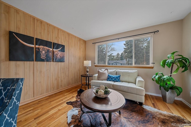 living area featuring wooden walls, wood finished floors, and baseboards