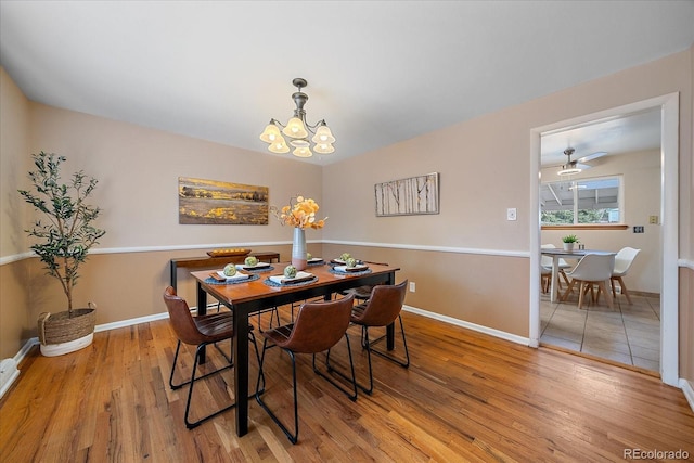 dining area with ceiling fan with notable chandelier, baseboards, and light wood-style floors