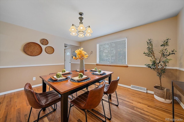 dining room with a notable chandelier, visible vents, light wood-style flooring, and baseboards