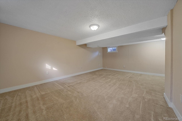 basement featuring a textured ceiling, baseboards, and carpet