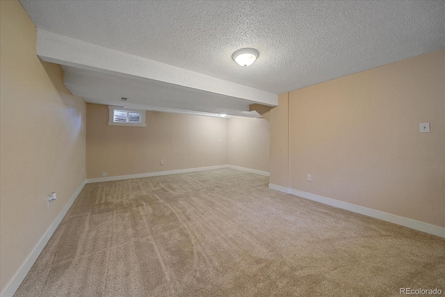 basement with light colored carpet, baseboards, and a textured ceiling