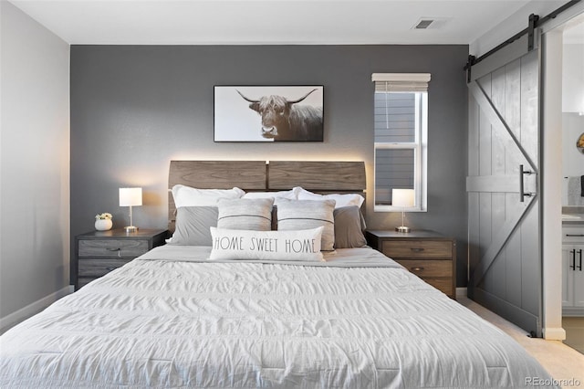 bedroom with a barn door and light carpet