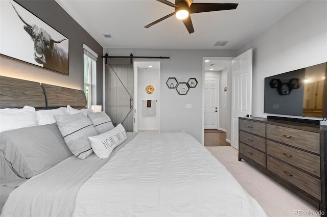 carpeted bedroom featuring ceiling fan and a barn door