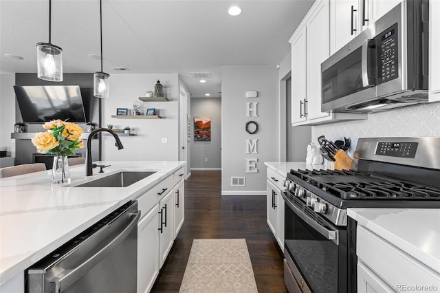 kitchen with white cabinets, sink, decorative light fixtures, appliances with stainless steel finishes, and dark hardwood / wood-style floors