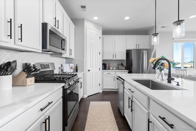 kitchen featuring white cabinetry, appliances with stainless steel finishes, hanging light fixtures, and sink