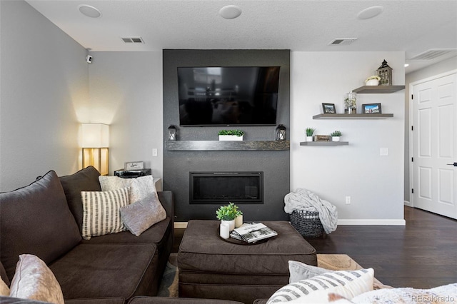 living room with a textured ceiling, a fireplace, and dark hardwood / wood-style floors