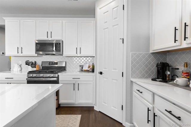 27491 E 10th Dr, Aurora, CO 80018 - kitchen featuring appliances with stainless steel finishes, white cabinetry, decorative backsplash, dark wood finished floors, and light stone counters