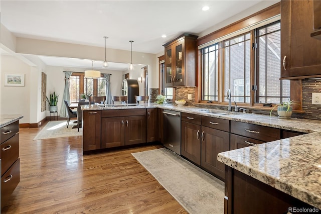 kitchen featuring a peninsula, decorative backsplash, stainless steel dishwasher, and a sink