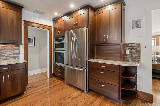 kitchen with stainless steel appliances, tasteful backsplash, light wood-type flooring, visible vents, and baseboards