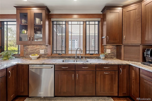 kitchen featuring backsplash, light stone countertops, a sink, and dishwasher