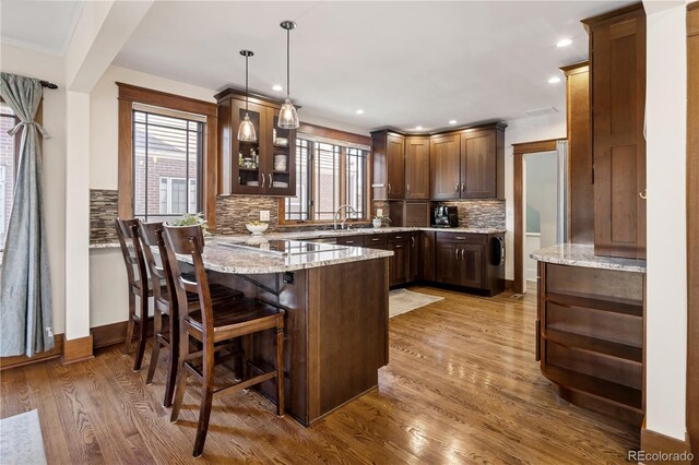 kitchen featuring backsplash, a breakfast bar, a peninsula, and wood finished floors