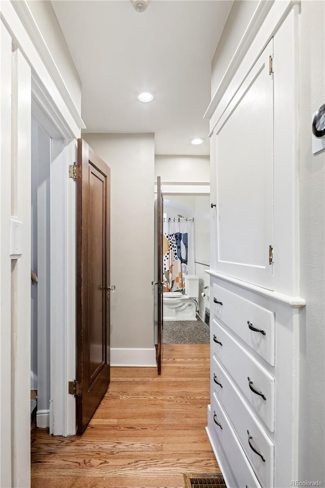 hallway with baseboards, light wood-style flooring, and recessed lighting