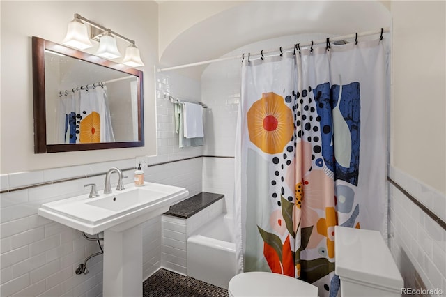 bathroom featuring tile walls, toilet, a wainscoted wall, and shower / bathtub combination with curtain