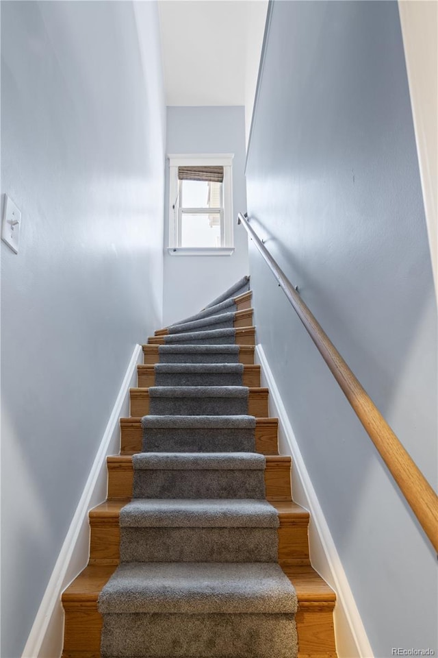 staircase featuring baseboards and wood finished floors
