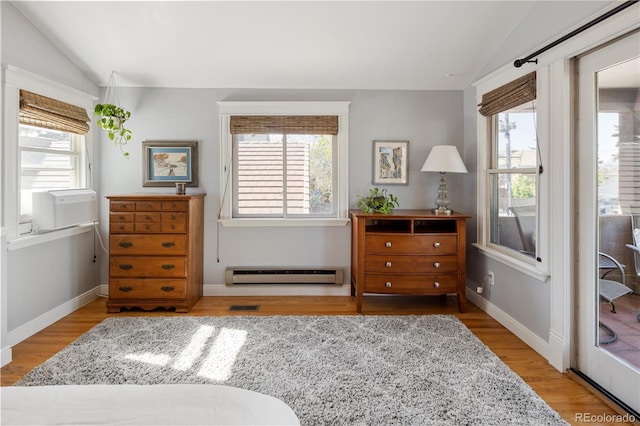 living area featuring lofted ceiling, a baseboard radiator, and a healthy amount of sunlight
