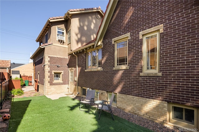 back of house featuring cooling unit, a yard, brick siding, and a fenced backyard
