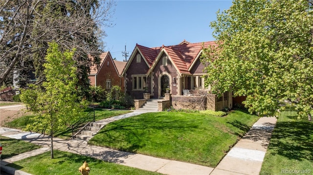 tudor home with a front lawn and brick siding