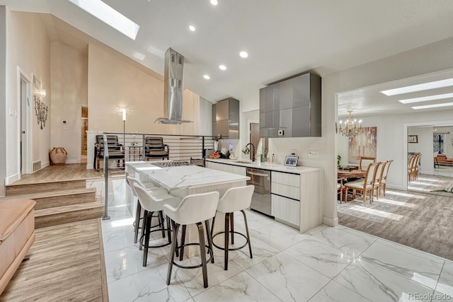 5173 S Emporia Way, Greenwood Village, CO 80111 - kitchen featuring a skylight, wall chimney exhaust hood, gray cabinets, appliances with stainless steel finishes, and modern cabinets
