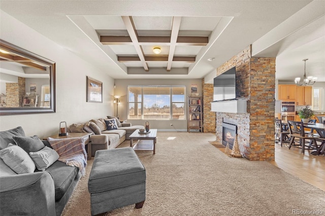 living room with an inviting chandelier, coffered ceiling, carpet floors, a stone fireplace, and beamed ceiling