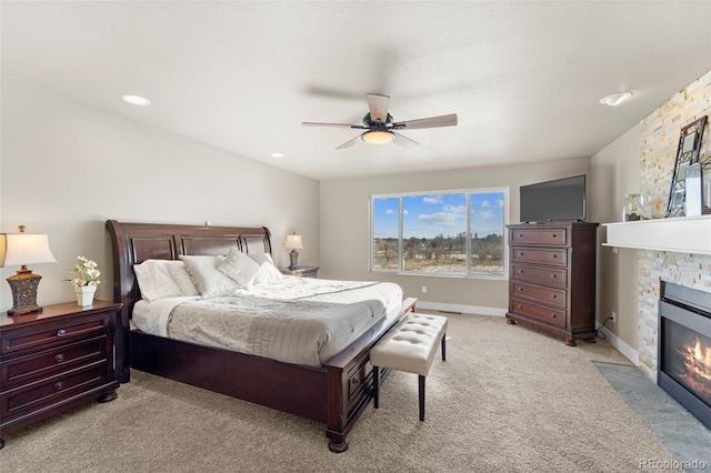 carpeted bedroom with ceiling fan and a fireplace