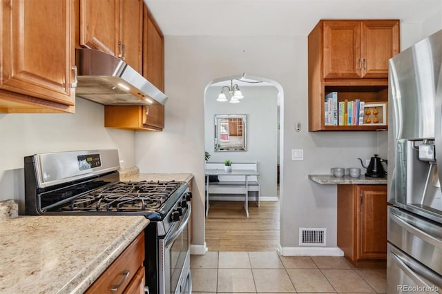 kitchen featuring a chandelier, light tile patterned floors, light stone countertops, and appliances with stainless steel finishes