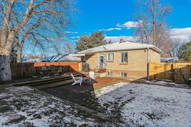 snow covered back of property with a patio