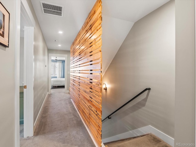 corridor featuring light carpet and wood walls