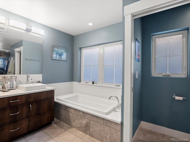 bathroom featuring tile patterned flooring, vanity, tiled bath, and decorative backsplash