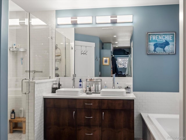 bathroom with tile walls, vanity, and independent shower and bath