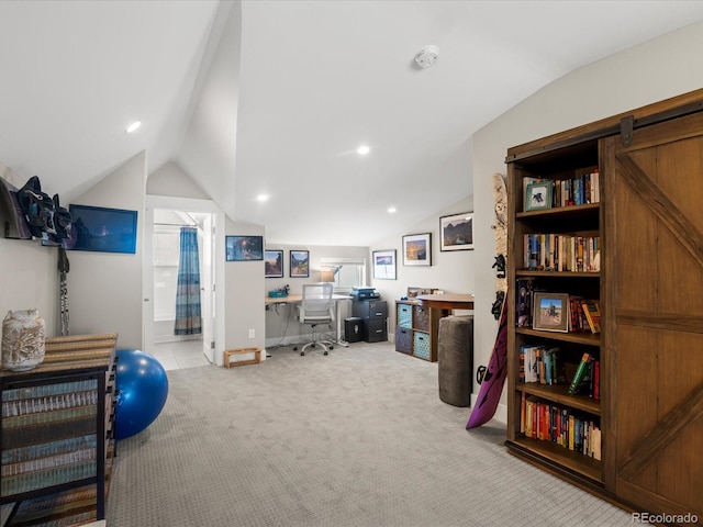 interior space featuring vaulted ceiling, a barn door, and light carpet