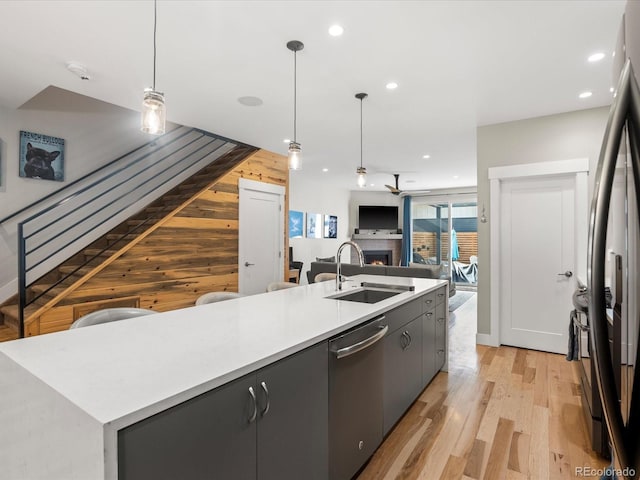 kitchen featuring sink, hanging light fixtures, wooden walls, a spacious island, and stainless steel dishwasher