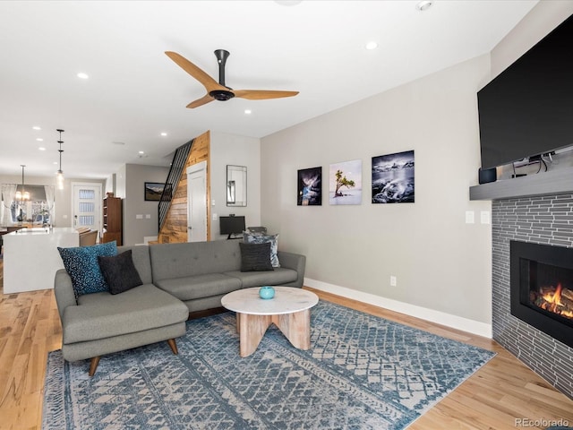 living room with hardwood / wood-style flooring, ceiling fan, and a tile fireplace