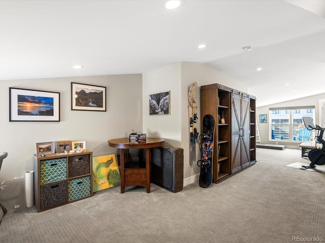 interior space featuring vaulted ceiling, a barn door, and carpet flooring