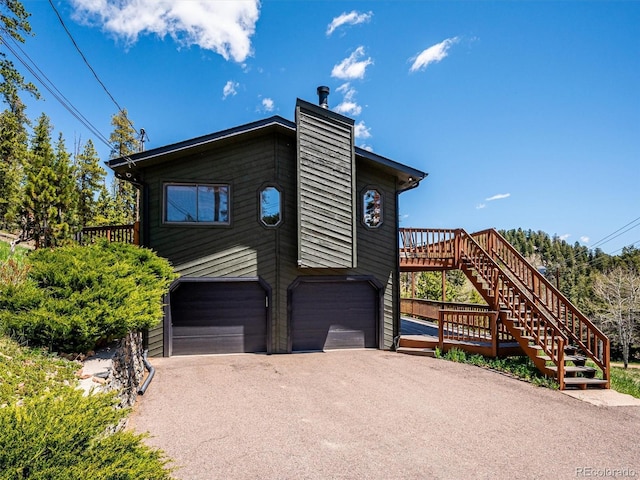 34075 Grouse Ln, Evergreen, CO 80439 - view of front of property featuring stairway, a garage, a chimney, and driveway