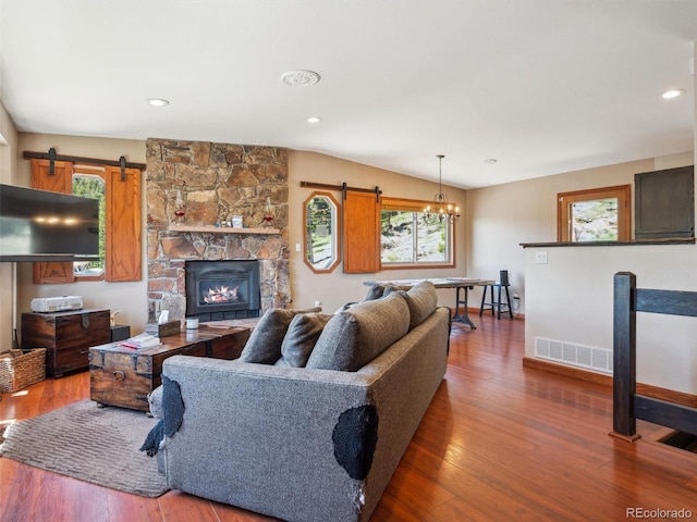 34075 Grouse Ln, Evergreen, CO 80439 - living room with a barn door, wood finished floors, a chandelier, baseboards, and a fireplace
