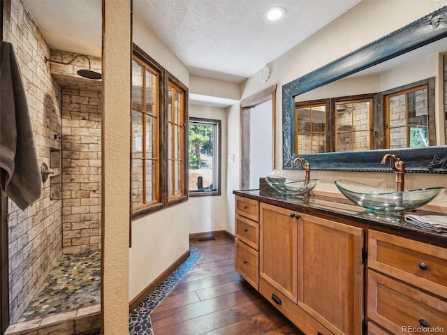 34075 Grouse Ln, Evergreen, CO 80439 - bar area featuring a sink, a textured ceiling, dark wood-style floors, and baseboards