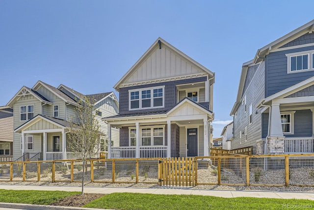 view of front of property with board and batten siding, a porch, and a fenced front yard