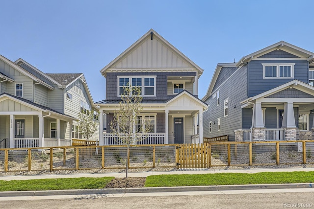 craftsman-style home featuring a fenced front yard, metal roof, a standing seam roof, a porch, and board and batten siding