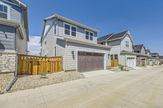 view of front facade featuring a garage, a residential view, fence, and driveway