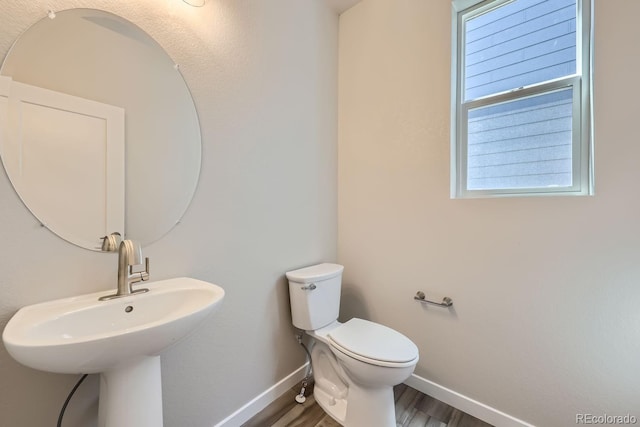 bathroom with baseboards, a sink, toilet, and wood finished floors